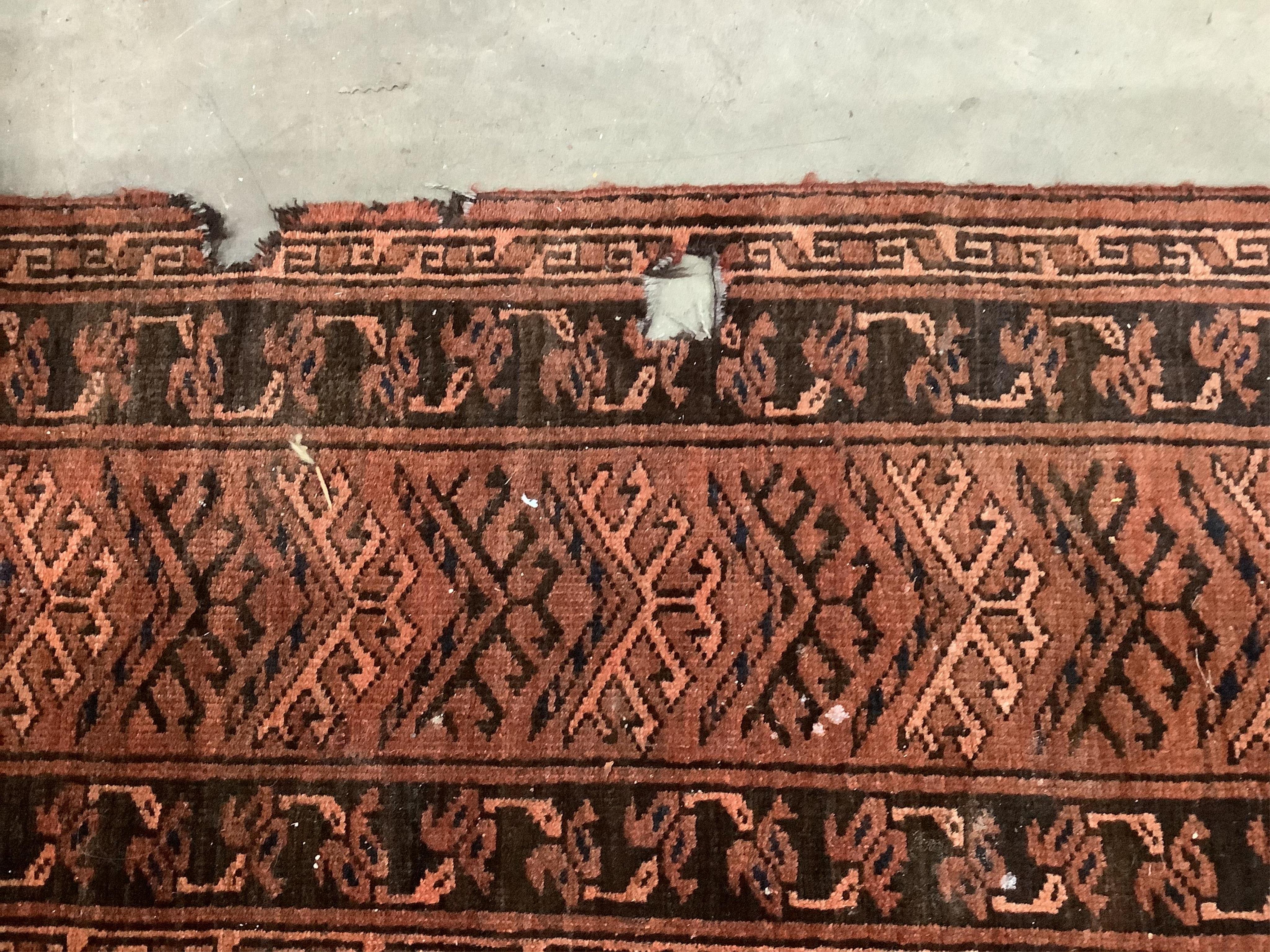 An Afghan rust ground carpet, 400 x 260cm. Condition - poor, damage to border